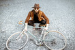 © rh2010 - Portrait of a bearded hipster dressed stylishly with brown hat and sweater sitting with retro bicycle on a pavement street