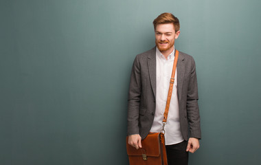 Wall Mural - Young redhead business man winking, funny, friendly and carefree gesture