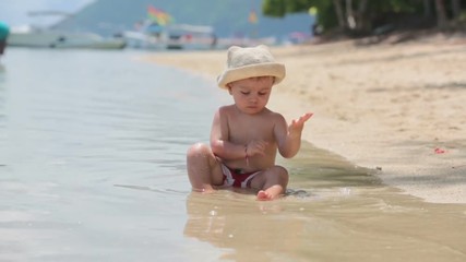 Wall Mural - Cute toddler baby boy playing with water on tropical beach