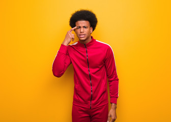 Wall Mural - Young sport black man over an orange wall doing a disappointment gesture with finger