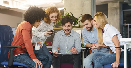 Wall Mural - Group of young coworkers discussing new marketing strategy in office