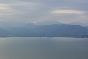 Poster - dramatic foggy weather mountain ridge silhouette along big lake waterfront 