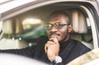 © xartproduction - A young businessman in a suit sits at the wheel of a expensive car.