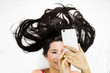© Nutt - Closeup portrait of happy asian women  lying on ground with black long hair. acting smile  , and plying phone
