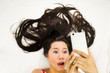 © Nutt - Closeup portrait of asian women  lying on ground with black long hair. acting wow , and plying phone.