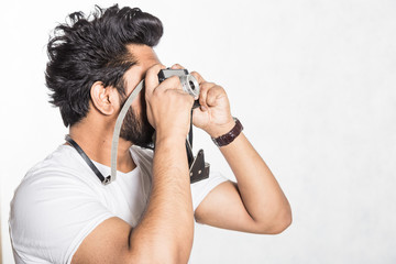 Sticker - Portrait of a handsome young stylish man with beard taking photo on a vintage camera.