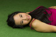 © Nutt - asian women lying on the green grass, a beautiful and dreamy Thai woman laying down on green grass, relaxing while looking at the camera, smiling.