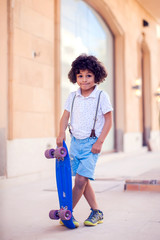 Wall Mural - Little boy with curly hair with skateboard. Children and entertainment concept