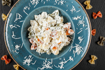 Wall Mural - Farfalle pasta in a creamy cheese sauce in plate on dark stone background. Top view, Flat lay. Vegetarian food