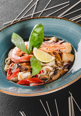 Wall Mural - Pasta spaghetti with seafood, langoustine, mussels, oysters, squid in mushrooms sauce on plate over dark stone background. Italian food