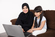 © Mahmoud Rahall - Arab woman teaching her daughter on laptop computer on white background