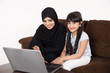 © Mahmoud Rahall - Arab woman teaching her daughter on laptop computer on white background