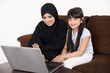 © Mahmoud Rahall - Arab woman teaching her daughter on laptop computer on white background