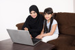 © Mahmoud Rahall - Arab woman teaching her daughter on laptop computer on white background
