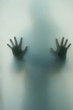 © Nedrofly - Ghostly silhouette of a girl with outstretched hands, fingers outstretched behind the translucent glass doorBlurred shadow of a horror woman. The hands on the glass.