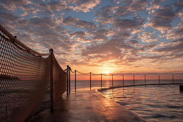 Wall Mural - Sunrise at Bronte Beach Pool, New South Wales, Australia. Waves on the rocks.