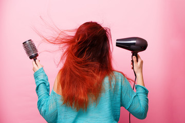 Woman holding a hairdryer on a pink background