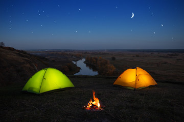 Wall Mural - orange and green tent by the river at night