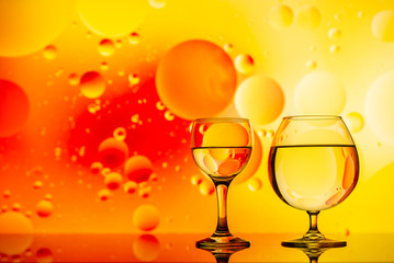 transparent glasses with water and oily drops on colorful background 