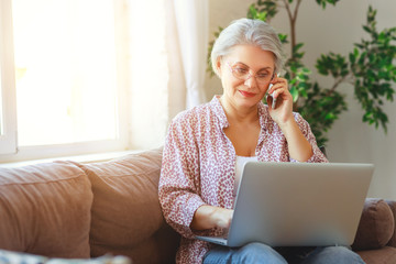 happy old woman senior working at computer laptop at home.
