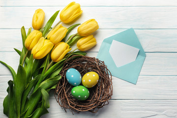 Easter background with bright, colored eggs in nest and yellow tulips