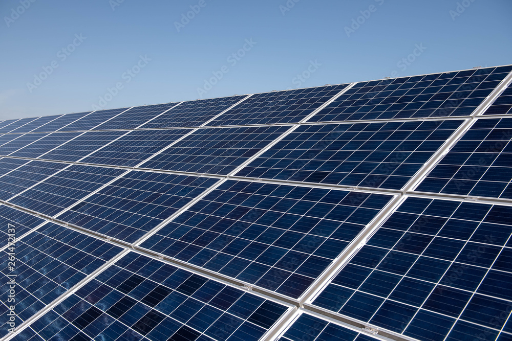 Close up clean solar panels on blue clear sky background producing friendly environment energy. Alternative electricity source - obrazy, fototapety, plakaty 