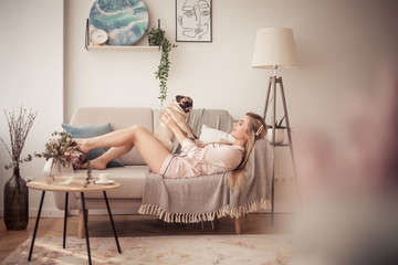 Lovely girl hugging her pug and playing with him in the house