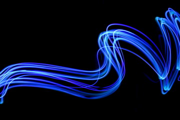 Wall Mural - Blue light painting photography, long exposure, blue streaks of vibrant color against a black background