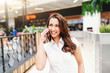 © Dusan Petkovic - Portrait of attractive caucasian woman with long brown hair dressed casual using smart phone in shopping mall.