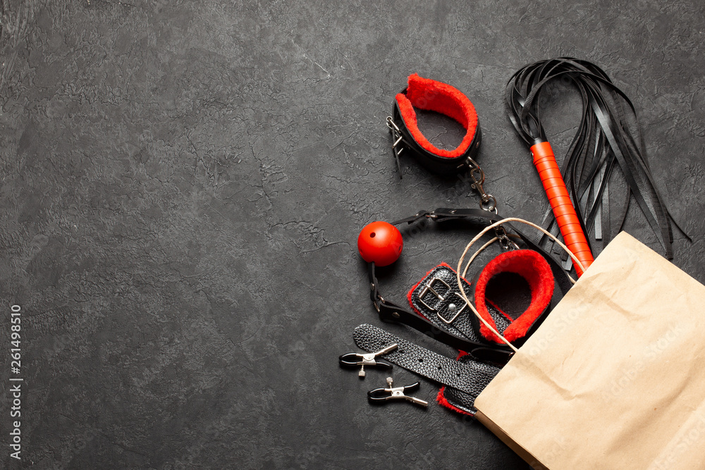 BDSM sex toys for adults. Shopping bag from a sex shop with a whip, gag,  handcuffs and leather straps. Copy space for text. Stock Photo | Adobe Stock