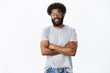 © Cookie Studio - Portrait of delighted calm and handsome african american male coworker in glasses with tattoos and pierced nose smiling joyfully and holding hands crossed on chest in confident pose as talking
