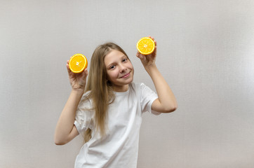 Cheerful beautiful girl holds in halves of orange halves. Positive emotions. Healthy food. Veggie and Vegan