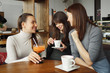 © lenblr - Three women girlfriends in a cafe are talking and drinking their beverages.