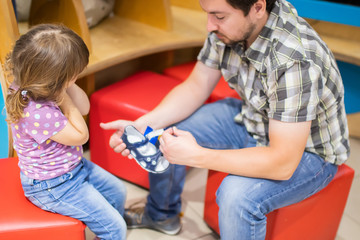 Cute little girl and her father choosing clothes in the shop.