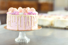 Pink Cake Decorated With Macaroons On The Table.