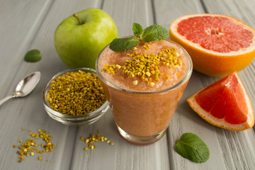 Wall Mural - Smoothies with grapefruit, green apple and  bee pollen on the grey wooden background