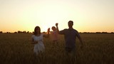 Fototapeta Natura - happy daughter with her mom and dad are walking across field of ripe wheat, baby is crumpling. An infant with parents playing and smiling in field with wheat. concept of happy family and childhood