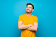 © luismolinero - Redhead man over blue wall looking up while smiling