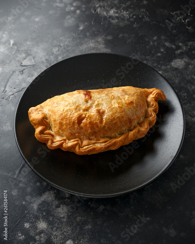 Fotomural Traditional Cornish pasty filled with beef meat, potato and vegetables on black