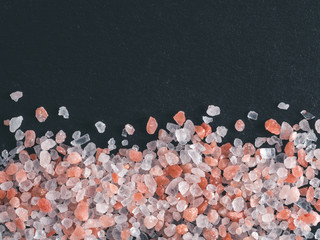 Wall Mural - Himalayan pink salt in crystals on black stone background. Copy space