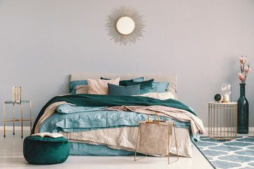 Wall Mural - Blue, beige and emerald green bedding on king size bed in contemporary bedroom interior with golden accents