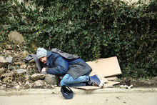 Poor Homeless Man Lying On Street In City