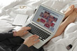 © New Africa - Woman holding laptop with open beauty blogger site on bed, closeup