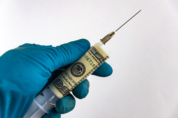 financial injections, money entry: a banknote of $ 100 inside a syringe for injections, in the person's hand