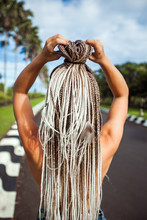A Girl With Long African Braids, In The Tropics Background Of Palm Trees.View Back