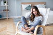 © BestForYou - Happy woman resting comfortably sitting on modern chair in the living room at home.