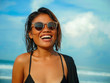 head and shoulders lifestyle portrait of young beautiful and sexy Asian girl in bikini and sunglasses enjoying holidays at tropical beach posing cool smiling happy at the sea