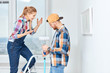 © alfa27 - Young woman sharing her interior design ideas, standing on a ladder while her boyfriend listen to her holding paint roller with a hand stick in empty white appartment.