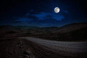mountain road through the forest on a full moon night. scenic night landscape of country road at nig