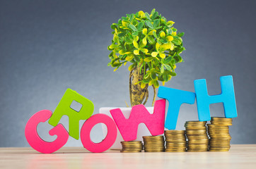 Business success concept, stacking coins and word GROWTH on wooden desk over beautiful reverberation gradient background